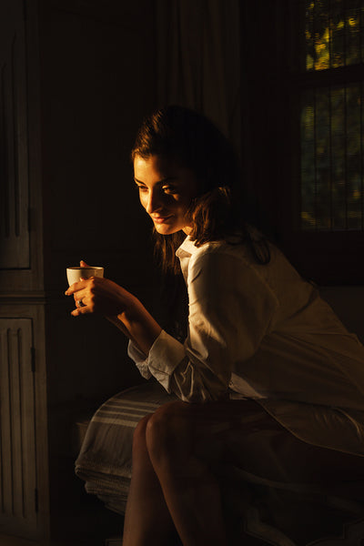 Glamorous young woman having a cup of coffee in her hotel room