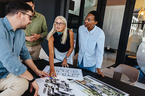 Team of diverse professionals discussing architectural designs in a modern office setting