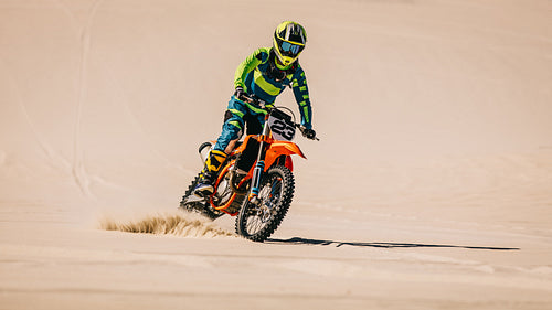 Moto racer riding upright in desert