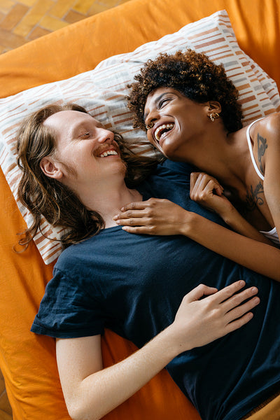 Joyful multicultural couple lying and laughing together