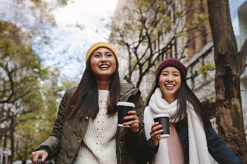 Asian women walking on street holding coffee