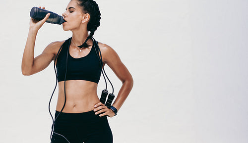 Portrait of female athlete drinking water