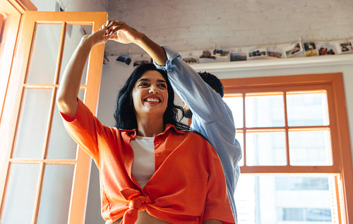 Cheerful Latin American couple dancing together indoors in a bright sunny room