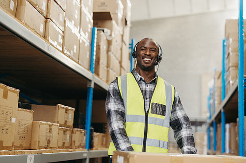 Happy warehouse picker smiling at the camera with a headset on