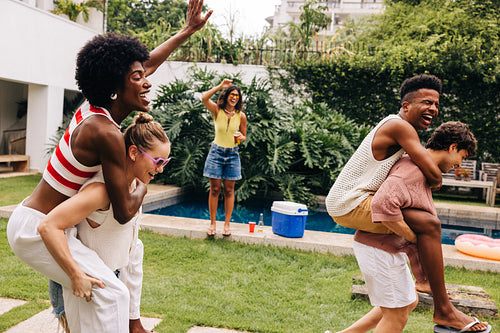 Friends play tag at backyard pool party