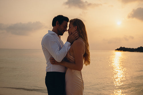 Romantic couple embracing at sunset on a tropical beach during a luxury vacation