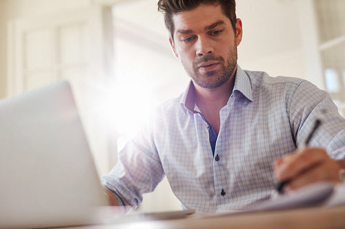Young businessman at home office taking notes