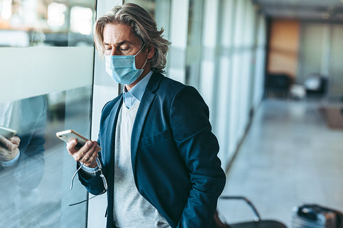 Business traveler with face mask waiting for his flight at airpo