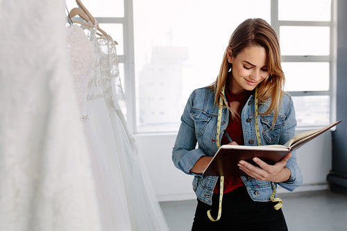 Dressmaker designing bridal wear pattern on diary