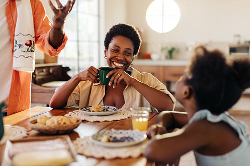 Mom smiling at her daughter during breakfast, enjoying the pão de queijo served by dad