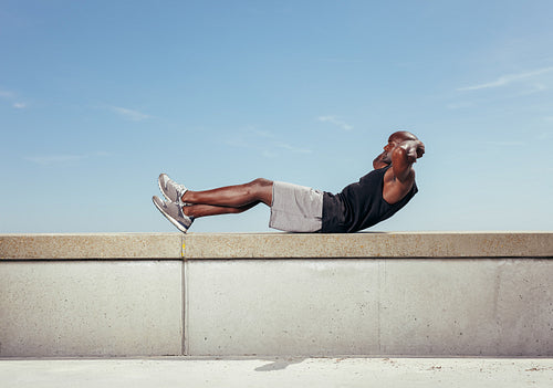 Athlete doing sit-ups against sky.