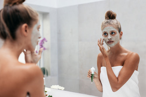 Beautiful woman applying mask to her face