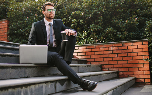Businessman relaxing outdoors with coffee and laptop