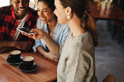 Woman taking pictures of coffee with friends