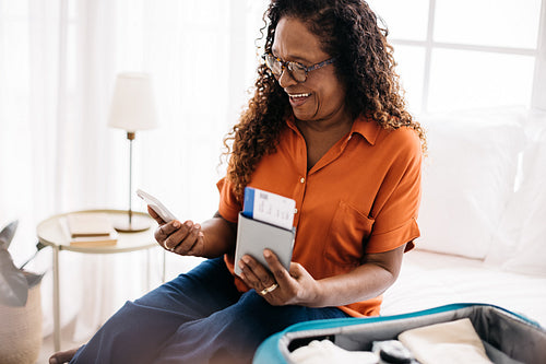 Mobile travel planning: Retired woman using her phone to book a hotel stay