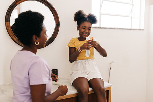 Mother and daughter practicing morning dental care with toothpaste