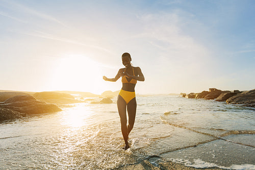 Woman in bikini coming out of the sea dancing