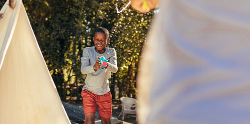 Boy playing squirt gun fight with friend