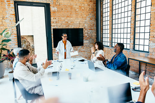 Successful boardroom meeting with diverse team applauding, celebrating achievements and offering congratulations in a modern office space