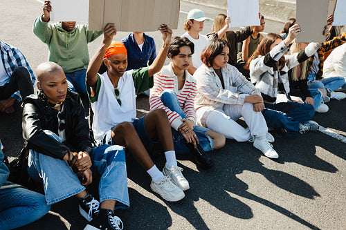 Diverse group of protestors sitting peacefully with signs outdoors