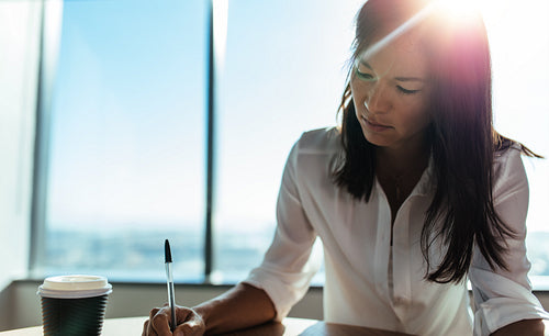 Closeup of a businesswoman sitting at coffee table doing office work.