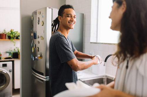 Smiling man washing dishes with his girlfriend