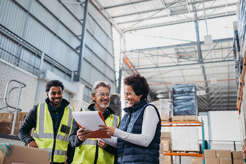 Happy warehouse workers looking at a report during a meeting