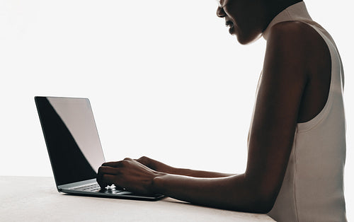 Woman typing on a laptop computer in a minimalistic setting