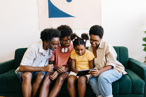 Happy Brazilian family watching a video on a tablet at home