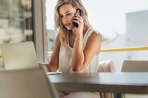 Businesswoman talking with client over phone in cafe