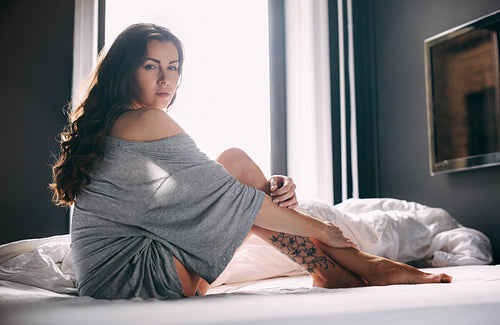 Beautiful young lady sitting on bed