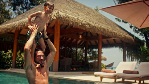 Joyful family playing and jumping in a private villa pool during a tropical vacation