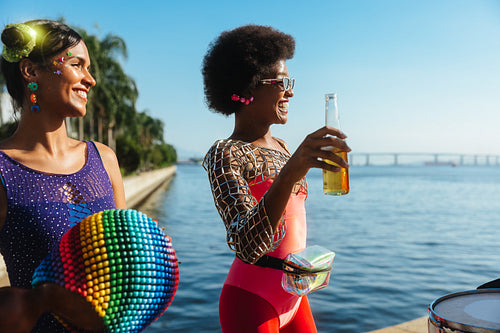 Women celebrate carnival by the water with drinks