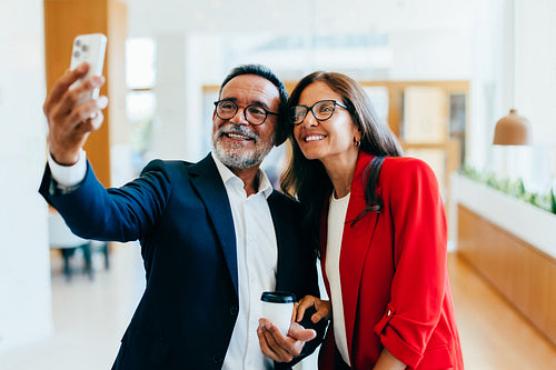 Senior business leaders smiling for a selfie during a casual coffee break