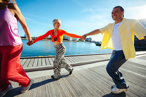 Friends walk hand in hand along the waterfront on a sunny summer day