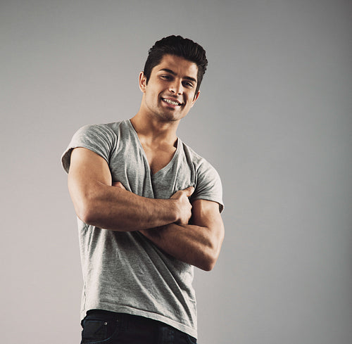 Smart young muscular man posing against grey background
