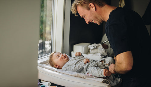 Caring father changing baby's diaper