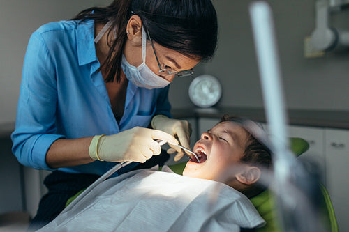 Pediatric dentist inspecting teeth of boy patient