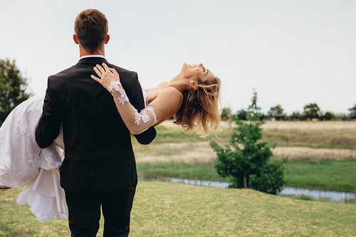 Bridegroom carrying bride and walking away