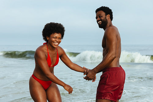 Joyful couple having fun at the beach enjoying sunny day