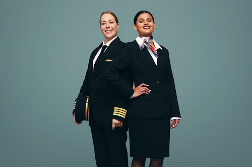 Confident pilot and flight attendant smiling at the camera in a 