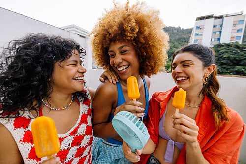Group of friends enjoying orange popsicles on a summer day outdoors