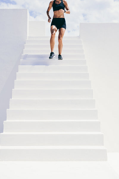 Female athlete running down the stairs of a building