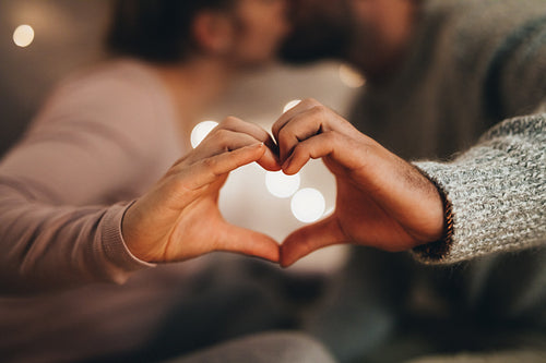 Close up of hands of a couple making a heart shape