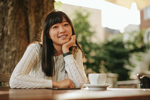 Attractive girl sitting at outdoor cafe and smiling