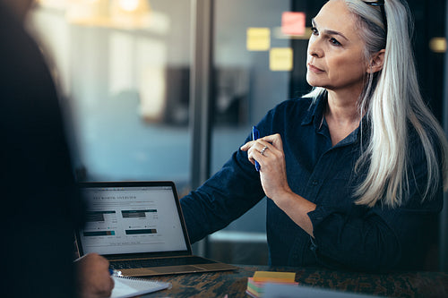 Business woman giving presentation on laptop to team