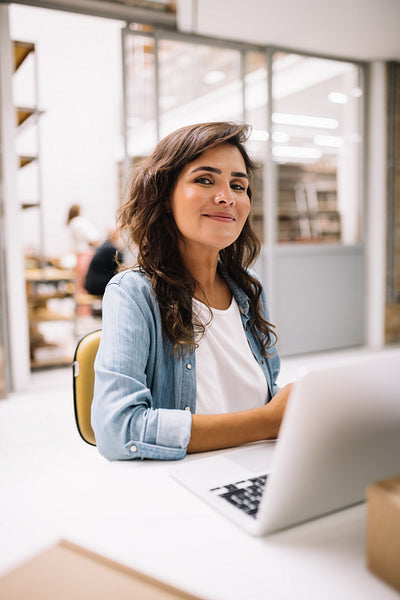 Confident female entrepreneur using a laptop in her warehouse