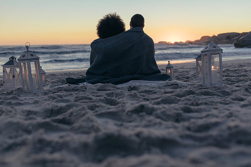 Couple sitting on the beach at sunset