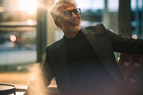 Smiling mature businessman sitting in office lobby
