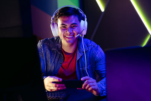 Gamer smiling at the camera as he watches a live stream of a game on his smartphone